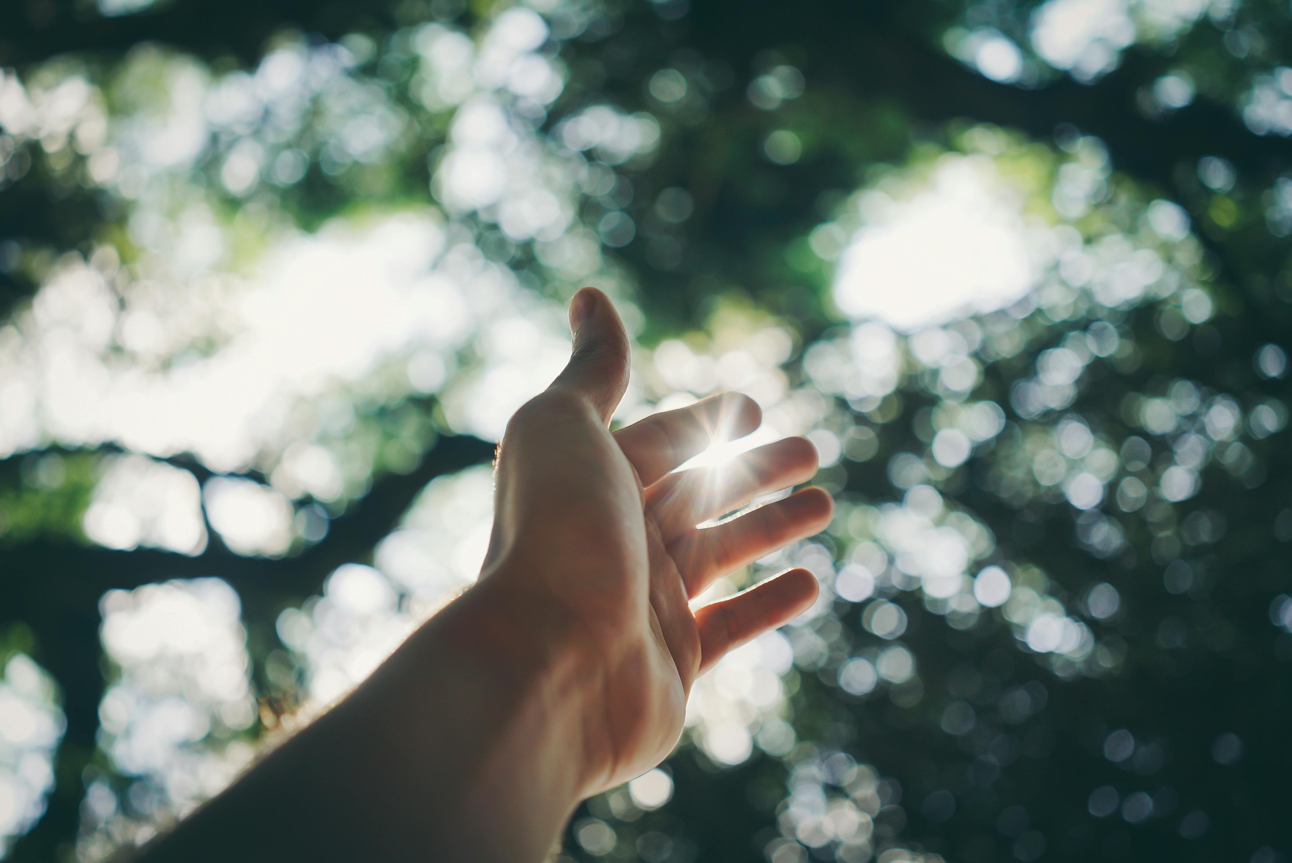 Mano extendida hacia la luz divina - símbolo de fe y esperanza